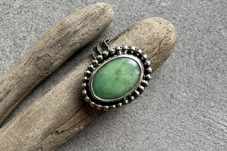 Srebrny pierścionek handmade z zielonym chryzoprazem o jabłkowym odcieniu. Surowa oprawa ze srebra przypominająca organiczne formy natury, tło stanowi drewno wyłowione z morza. Chryzopraz pierścionek kulki