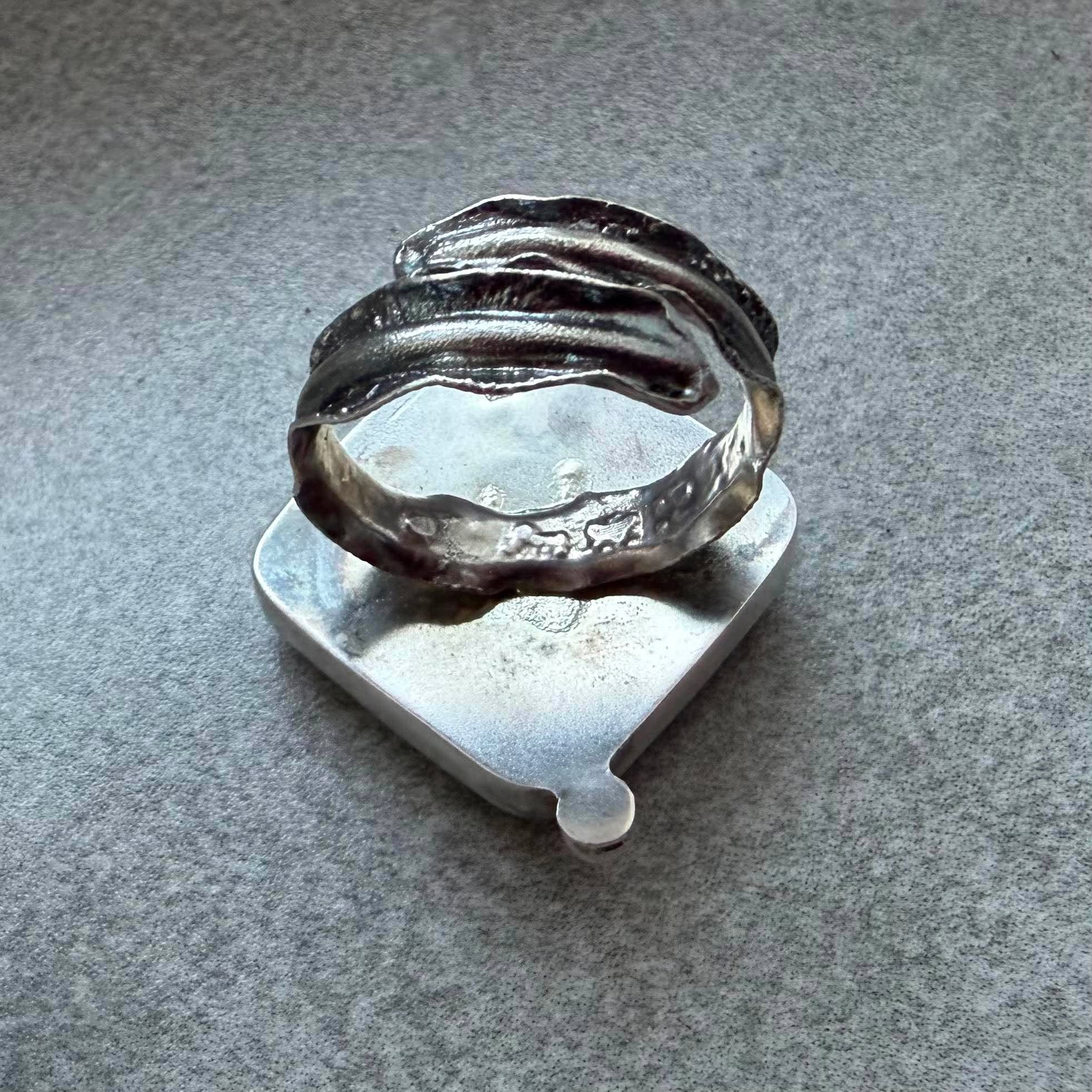 Kwadratowy pierścionek z zielonym awenturynem ze srebra 925 na dłoni. Zielony awenturyn kwadrat 22x22 mm gładki szlif ze srebrną kulką. Jasna polerowana kwadratowa oprawa i przyciemniana srebrna obrączka. Duży kwadratowy pierścionek z zielonym awenturynem regulowany Kwadratowy pierścionek z zielonym awenturynem ze srebra 925 na dłoni. Zielony awenturyn kwadrat 22x22 mm gładki szlif ze srebrną kulką. Jasna polerowana kwadratowa oprawa i przyciemniana srebrna obrączka. Duży kwadratowy pierścionek z zielonym awenturynem regulowany