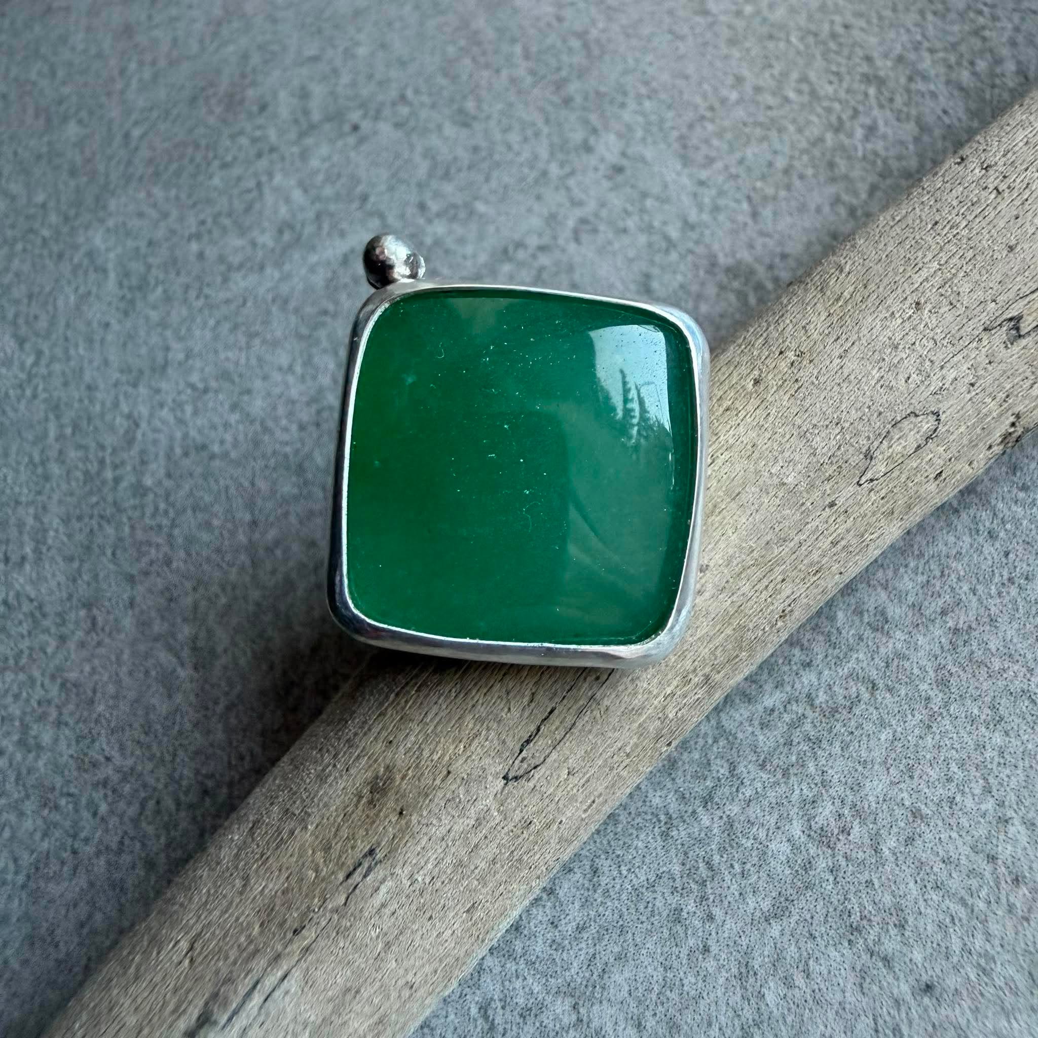 Kwadratowy pierścionek z zielonym awenturynem ze srebra 925 na dłoni. Zielony awenturyn kwadrat 22x22 mm gładki szlif ze srebrną kulką. Jasna polerowana kwadratowa oprawa i przyciemniana srebrna obrączka. Duży kwadratowy pierścionek z zielonym awenturynem regulowany Kwadratowy pierścionek z zielonym awenturynem ze srebra 925 na dłoni. Zielony awenturyn kwadrat 22x22 mm gładki szlif ze srebrną kulką. Jasna polerowana kwadratowa oprawa i przyciemniana srebrna obrączka. Duży kwadratowy pierścionek z zielonym awenturynem regulowany